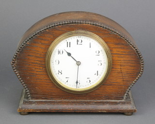 A 1930's French bedroom timepiece with enamelled dial and Arabic numerals contained in an oak arch shaped case 