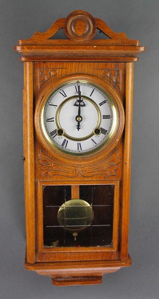 A striking wall clock with enamelled dial and Arabic numerals contained in a carved oak case