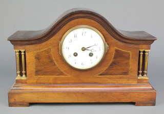 A 1930's French 8 day striking mantel clock with enamelled dial and Arabic numerals contained in an arched inlaid mahogany case having gilt columns to the side