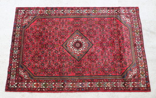 A red ground Persian rug with diamond to the centre and floral ground 88" x 60" 