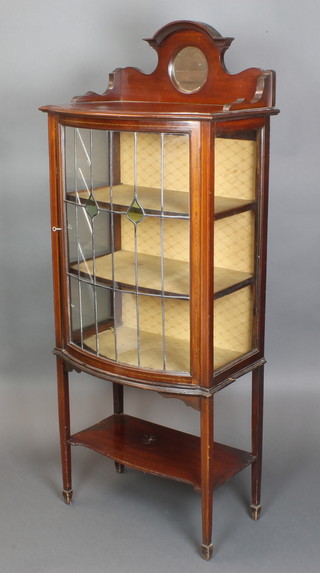 An Edwardian inlaid mahogany bow front display cabinet, the raised mirrored back with 3/4 gallery above a cupboard fitted 3 shelves enclosed by lead glazed panelled doors, raised on square tapering supports with undertier, 63"h x 25"w x 15"d 