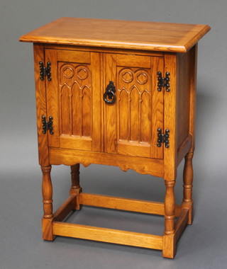 An Ipswich style carved oak cabinet enclosed by panelled doors, raised on turned and block supports 27"h x 20"w x 13"d 