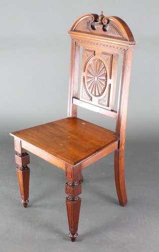 A Victorian carved mahogany hall chair with broken pediment to the back and carved panel, solid seat, raised on square supports 