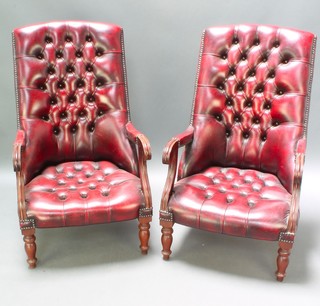 A pair of William IV style mahogany open arm chairs upholstered in red buttoned leather, raised on turned supports