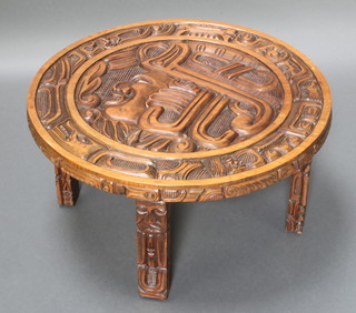 A circular "Aztec" mahogany occasional table, the top carved a portrait bust, the 4 legs in the form of totem poles  16"h x 29 1/" diam. 