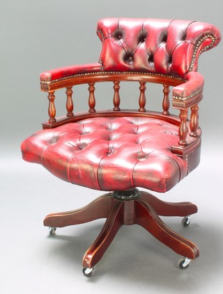 A tub back revolving office chair upholstered in red buttoned leather 