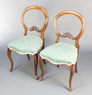 A pair of Victorian walnut balloon back dining chairs with carved mid rails and seats of serpentine outline 