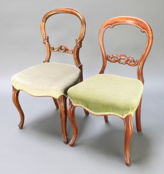 A pair of Victorian carved mahogany balloon back dining chairs with carved mid rails and seats of serpentine outline, raised on cabriole supports 