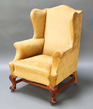 A Georgian style winged armchair upholstered in yellow Dralon, raised on carved cabriole, ball and claw supports with H framed stretcher 