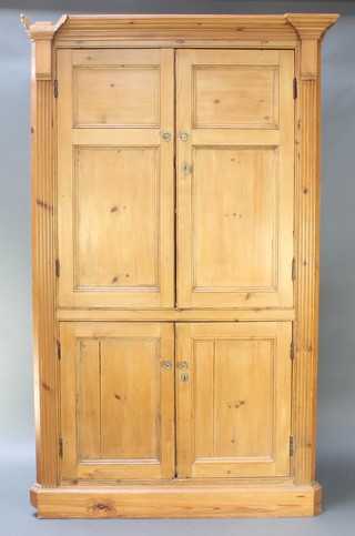 A 19th Century pine double corner cabinet with moulded cornice and fluted columns to the side, the upper section fitted a cupboard enclosed by panelled doors, the base enclosed by panelled doors 81"h x 51"w x 44"d 
