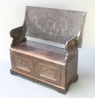 A Victorian carved oak monks bench the base fitted a cupboard enclosed by panelled doors 30"h x 41 1/2"w x 20"d 