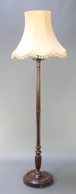 A turned and reeded standard lamp, raised on a circular base 