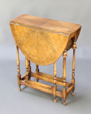 A Queen Anne style quarter veneered drop flap spider leg gateleg table with crossbanded top, raised on turned cup and cover supports, 24"h x 20"w x 7" when closed x 30" when extended  