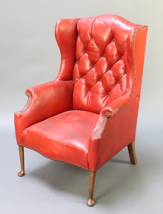 A Georgian style winged armchair upholstered in red buttoned rexine, raised on club supports 
