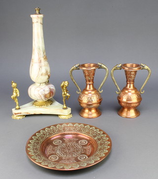 A turned onyx and gilt metal table lamp raised on a triform base supported by figures 16", a pair of copper and brass twin handled vases 8", a circular engraved copper dish 10" 