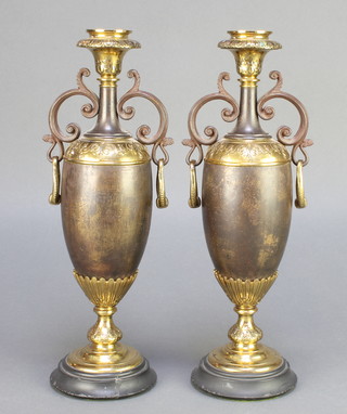 A pair of Victorian bronze and gilt mounted twin handled urns, raised on spreading feet 13" 