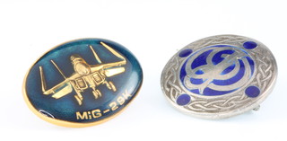 From the estate of Captain Eric M Brown A Mig 29K pin and a Celtic style silver and enamelled badge with monogram