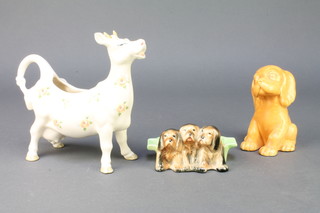 A Sylvac style figure of an orange seated dog 4", a Beswick ashtray with 3 hounds 4" and a Beswick cow creamer  7" 