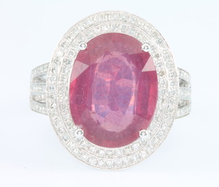 A 14ct white gold oval ruby and diamond ring, the centre stone approx. 6.9ct surrounded by 2 rows of brilliant cut diamonds approx. 1.0ct, size M 1/2