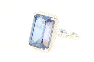 A 14ct white gold sapphire and diamond ring, the rectangular cut centre stone approx. 11.20ct surrounded by brilliant cut diamonds approx 0.4ct, size M 