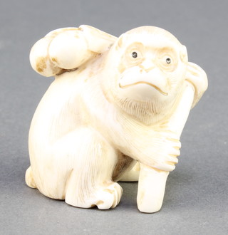 A Japanese carved ivory Netsuke in the form of a seated monkey holding fruit on his back 1 1/2" 