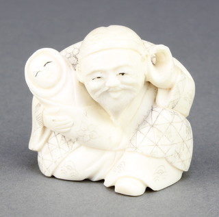 A Japanese carved ivory Netsuke in the form of a seated elderly man holding a baby with his hand to his ear, signed 1 1/2" 