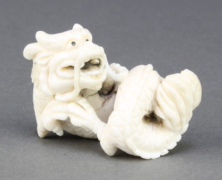 A Japanese carved ivory Netsuke in the form of a reclining dragon with open mouth, signed 1 3/4" 