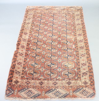A red ground Afghan rug with 30 octagons to the centre 32" x 43", in wear and missing a small 4" section to the side