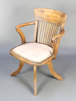 An Edwardian bleached oak stick and bar back revolving office chair 