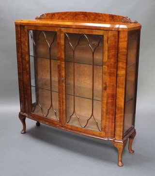 An Art Deco walnut display cabinet with raised back, fitted adjustable shelves enclosed by astragal glazed panelled doors, raised on cabriole supports 50 1/2"h x 46"w x 14"d 
