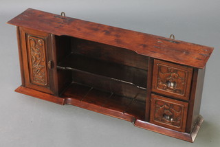 A Chinese carved hardwood hanging cabinet with carved bat decoration, fitted a recess with shelf flanked by a cupboard and 2 short drawers 14"h x 34"w x 7"d 