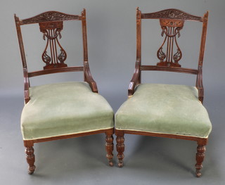 A pair of Edwardian carved walnut nursing chairs with pierced vase shaped backs and upholstered seats, raised on turned and reeded supports 