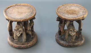 A pair of "Bamileke" circular carved wooden stools decorated leopards and supported by 2 figures 15"h x 13" diam.  