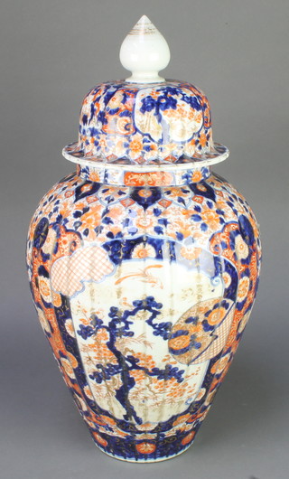 A late 19th Century Imari oviform vase with ribbed decoration and high dome lid, decorated with panels of trees and flowers with exotic birds 21" 