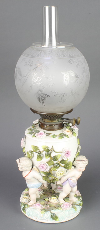 A 19th Century German porcelain table lamp supported by 3 cherubs and applied flowers with etched glass shade 21" 