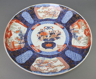 An early 20th Century Imari shallow dish, the centre decorated with a basket of flowers surrounded by 4 vignettes of garden landscapes with pavilions 18 1/2"  