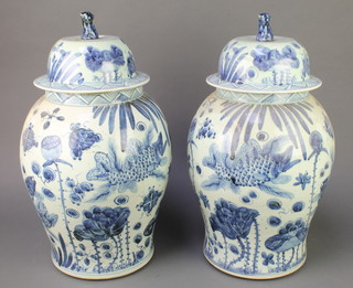 A pair of modern Chinese blue and white baluster vases and covers with Shi Shi finials, the body decorated with panels of carp amongst seaweed 21" 