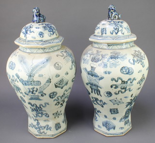 A pair of 20th Century Chinese octagonal baluster vases and covers with Shi Shi finials, the bodies decorated with classical motifs 18" 
