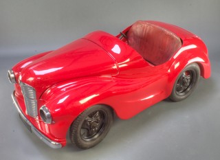 An Austin J40 tin plate pedal car, by the Austin Junior Car Factory, this car was manufactured in 1955 the first year of production during which 1149 were made, it is numbered 16442 (having started at 16001).   The pedal car has been resprayed in bright red and has its original tyres and seat back to the interior 54"l, 19"h x 25"w 