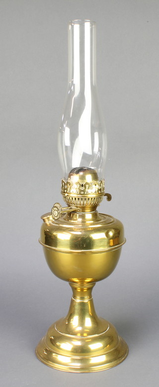 A brass oil lamp with clear glass chimney