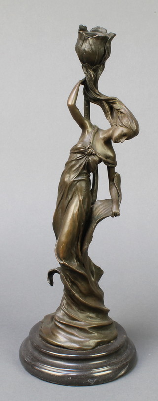 An Art Nouveau style bronze candlestick in the form of a standing maiden, raised on an oval base 13" 