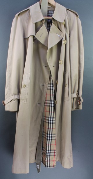A Burberry cream double breasted raincoat complete with belt together with a lady's blue Burberry raincoat