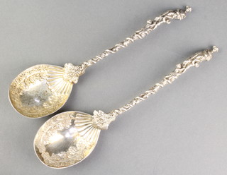A pair of Victorian silver serving spoons with fancy handles and figural terminals with shell bowls having vinous decoration London 1890, 234 grams
