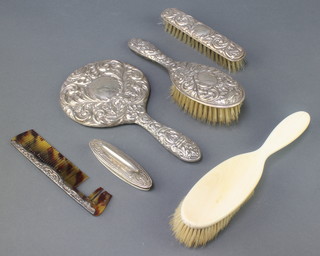 A repousse silver 4 piece brush set with hand mirror, clothes brush, hair brush and comb Birmingham 1969, a plated nail buffer and an ivory brush 