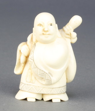 A Japanese carved ivory Netsuke in the form of a deity holding a sack on his back, signed 2" 