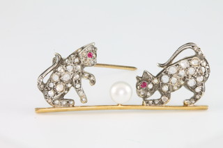 An Edwardian style yellow gold diamond, ruby and pearl set brooch in the form of 2 cats playing with a ball 