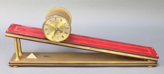 A Dent of London Incline gravity clock with gilt metal barrel case, silvered dial with Roman numerals, on a leather mounted platform  