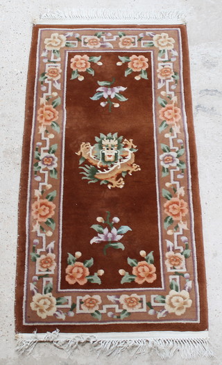 A brown ground Chinese rug with dragon decoration to the centre within floral borders 57" x 28" 