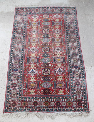 A red ground Caucasian carpet with numerous octagons to the centre within a multi row border 112" x 63" 