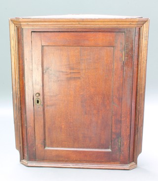 An 18th Century oak hanging corner cabinet with moulded cornice, fitted shelves enclosed by a panelled door 35 1/2"h x 31"w x 16"d 
